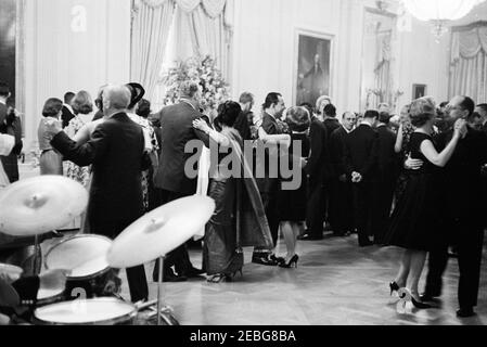 Accoglienza diplomatica alle 18:00. Gli ospiti ballano presso un ricevimento diplomatico presso la Casa Bianca. Assistente speciale al presidente, Frederick G. Dutton, danza con una donna non identificata a destra. Anche nella foto: Primo segretario stampa Ladyu2019s, Pamela Turnure (a sinistra); primo segretario sociale Ladyu2019s, Letizia Baldrige (a destra, parzialmente nascosto). Camera Est, Casa Bianca, Washington, D.C. Foto Stock