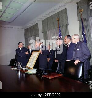 Firma della proclamazione - Voluntary Overseas Aid Week, 11:30. I leader delle organizzazioni umanitarie e religiose americane presentano il presidente John F. Kennedy con un scroll incorniciato citando il suo u0022vigoroso campionato di assistenza costruttiva ai bisognosi abroadu0022 durante la firma della proclamazione che designa la settimana del 9 aprile 1962, come Voluntary Overseas Aid Week. (L-R) non identificato (in dietro, per lo più nascosto); Rabbi Herbert A. Friedman, Vice Presidente Esecutivo dell'appello ebraico Unito; Richard W. Reuter, Direttore Esecutivo DELL'ASSISTENZA; Fowler Hamilton, Amministratore dell'Agenzia per Foto Stock