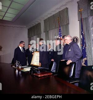 Firma della proclamazione - Voluntary Overseas Aid Week, 11:30. I leader delle organizzazioni umanitarie e religiose americane presentano il presidente John F. Kennedy con un scroll incorniciato citando il suo u0022vigoroso campionato di assistenza costruttiva ai bisognosi abroadu0022 durante la firma della proclamazione che designa la settimana del 9 aprile 1962, come Voluntary Overseas Aid Week. (L-R) non identificato (in dietro, per lo più nascosto); Rabbi Herbert A. Friedman, Vice Presidente Esecutivo dell'appello ebraico Unito; Richard W. Reuter, Direttore Esecutivo DELL'ASSISTENZA; Fowler Hamilton, Amministratore dell'Agenzia per Foto Stock