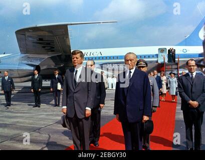 Viaggio in Europa: Germania, Bonn: Arrivo, Konrad Adenauer, Cancelliere della Germania occidentale nella foto. Il presidente John F. Kennedy è in piedi con il Cancelliere della Germania occidentale, Konrad Adenauer (cappello), durante la cerimonia di arrivo all'aeroporto di Wahn a Bonn, Germania occidentale (Repubblica federale). Alle spalle del presidente Kennedy e del cancelliere Adenauer (L-R): Ministro federale della difesa della Germania occidentale, Kai-Uwe von Hassel; Ispettore generale della Bundeswehr, generale Friedrich A. Foertsch; interprete del ministero degli Affari esteri tedesco, Heinz Weber. In piedi su tappeto rosso sullo sfondo: Ministro degli Affari Esteri o Foto Stock