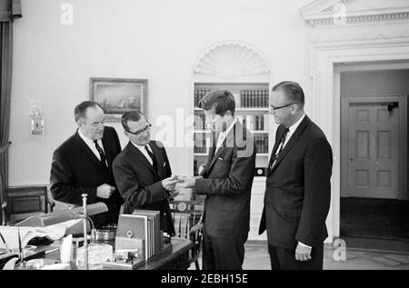 Visita di Robert J. Linney, presidente della riserva mineraria, senatore Hubert H. Humphrey, e rappresentante John A. Blatnikrn(Minnesota), 9:55. Il presidente John F. Kennedy e il presidente della Reserve Mining Company, Robert J. Linney, tengono un oggetto non identificato durante una visita nell'ufficio ovale. Da sinistra a destra: Senatore Hubert H. Humphrey, Jr. (Minnesota); Sig. Linney; Presidente Kennedy; Rappresentante John A. Blatnik (Minnesota). Ufficio ovale, Casa Bianca, Washington, D.C. Foto Stock