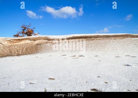 Neve, un deposito di neve e una certa sabbia scolpita dal vento in un tumulo durante una tempesta di neve Foto Stock