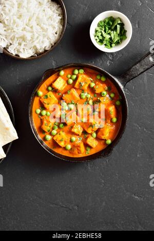 Paneer burro masala. Ricciolo di formaggio di stile indiano curry in padella su sfondo di pietra nera con spazio libero di testo. Vista dall'alto, disposizione piatta Foto Stock