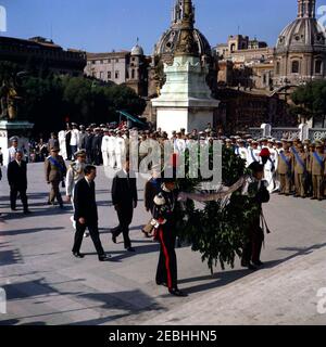 Viaggio in Europa: Italia, Roma: Il Presidente Kennedy alla Tomba del Milite Ignoto. Il presidente John F. Kennedy cammina verso la Tomba del Milite Ignoto al Monumento Vittorio Emanuele (u201cMonumento Nazionale a Vittorio Emanuele IIu201d) a Roma, Italia. Due membri della polizia militare italiana (Carabinieri) camminano di fronte al presidente, portando una corona per deporre alla tomba per suo conto. Camminando dietro Carabinieri (L-R): Ufficiale militare non identificato (sul retro, con indosso il bianco); Capo del protocollo italiano, Angelo Corrias; ufficiale militare non identificato; Aide navale al presidente Kennedy, CA Foto Stock