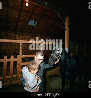 Caroline Kennedy (CBK) u0026 John F. Kennedy, Jr. (JFK, Jr.), presso Fort Myer Stables. John F. Kennedy, Jr. (Tenuto da un uomo non identificato, che tiene le redini di un cavallo), visita le scuderie di Fort Myer ad Arlington, Virginia. Foto Stock