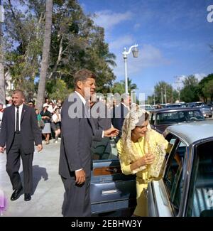 Il Presidente e la Sig.ra Kennedy partono dalla chiesa di St. Edward, Palm Beach, Florida, dopo i servizi, alle 11:45. Il presidente John F. Kennedy e la First Lady Jacqueline Kennedy entrano in una macchina dopo la messa alla chiesa cattolica di St. Edwardu2019 a Palm Beach, Florida. Il primo cognato di Ladyu2019s, il Principe Stanislao Radziwill di Polonia, si erge dietro di lei sullo sfondo. Anche nella foto: White House Secret Service agenti, Don Lawton e Floyd noing. Foto Stock