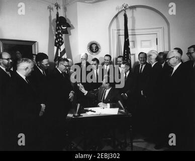 Firma della fattura - S.R. 11970 Legge pubblica 87-794, Legge di espansione di commercio di 1962, 12:10. Il presidente John F. Kennedy (seduto) distribuisce le penne dopo aver firmato il Trade Expansion Act del 1962. In piedi (L-R): Non identificato; Rappresentante John J. Flynt Jr. (Georgia); Rappresentante Hale Boggs (Louisiana); Segretario della Difesa, Robert S. McNamara (in dietro, per lo più nascosto); Rappresentante Wilbur D. Mills (Arkansas); Senatore Harry Flood Byrd della Virginia (che riceve una penna dal Presidente Kennedy); Senatore Robert S. Senatore Mike Mansfield (Montana); Sen Foto Stock