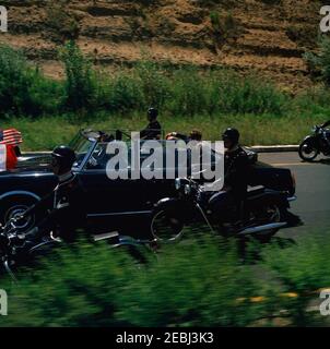 Viaggio in Europa: Italia, Napoli: Moto, 17:40. Il presidente John F. Kennedy (indossando occhiali da sole) giace sul sedile posteriore di un convertibile aperto mentre la sua motocicletta viaggia attraverso Napoli, Italia. Antonio segni, presidente d'Italia, siede con il presidente Kennedy. L'agente White House Secret Service, Gerald A. u201cJerryu201d Behn, si trova nel sedile centrale anteriore. Un accompagnatore di moto viaggia con l'auto. Foto Stock