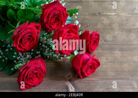 Bouquet di rose rosse sul tavolo di legno in luci solari ad angolo. Bel regalo per il saluto con San Valentino o il giorno della Madre. Foto Stock