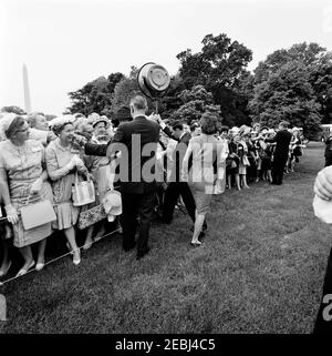 Visita dei partecipanti alla Conferenza della Campagna 1962 per le Donne democratiche, alle 9:35. Il Presidente John F. Kennedy, la First Lady Jacqueline Kennedy e il Vice Presidente Lyndon B. Johnson salutano i partecipanti alla Campagna 1962 per le Donne democratiche. Il monumento di Washington è visibile sullo sfondo. South Lawn, Casa Bianca, Washington, D.C. Foto Stock