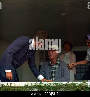 Viaggio a Hyannis Port u2013 Squaw Island, 1963-08-14. Il presidente John F. Kennedy visita con suo padre, l'ambasciatore Joseph P. Kennedy, Sr., sul portico della sua casa a Hyannis Port, Massachusetts. La nipote Ambassadoru2019s, Ann Gargan, si trova sul bordo più a destra della cornice. Foto Stock