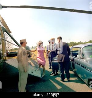 Viaggio a Hyannis Port u2013 Squaw Island, 1963-08-14. Il presidente John F. Kennedy e la First Lady Jacqueline Kennedy salono a bordo di un elicottero durante una visita a Squaw Island; osservano tre uomini non identificati. Porto di Hyannis, Massachusetts. Foto Stock