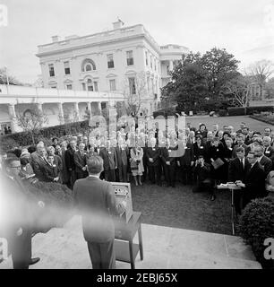 Visita dei delegati alla sessione 1963, Consiglio di Gestione del Comitato consultivo per gli Studi postali, Unione postale universale, 9:35. Il presidente John F. Kennedy (a leggio, con ritorno alla telecamera) esprime le sue osservazioni ai delegati internazionali della sessione 1963 dell'Unionu0027s del Consiglio di Gestione del Comitato consultivo per gli Studi postali. Il Vice Presidente del Postmaster Generale, Sidney W. Bishop, si trova a sinistra del Presidente Kennedy; uno stenografo non identificato, si trova all’estrema destra. Rose Garden, White House, Washington, D.C. [il blemish nella parte inferiore sinistra dell'immagine è originale al Foto Stock