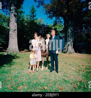 Presidente Kennedy, First Lady Jacqueline Kennedy (JBK), Caroline Kennedy (CBK) u0026 John F. Kennedy, Jr. (JFK, Jr.), con pony u201cLeprechaunu201d, dono del Presidente d'Irlanda u00c9amon de Valera. Il presidente John F. Kennedy, First Lady Jacqueline Kennedy, e i loro figli, Caroline Kennedy e John F. Kennedy, Jr., stanno con un pony Connemara, Leprechaun, dato in dono dal presidente d'Irlanda, u00c9amon de Valera. South Lawn, Casa Bianca, Washington, D.C. Foto Stock