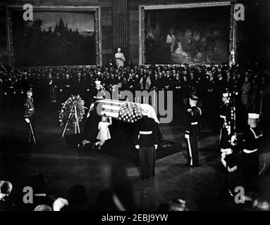 Funerale di Stato del presidente Kennedy: Giacere nello stato al Campidoglio degli Stati Uniti, partenza della famiglia Kennedy. Il defunto presidente John F. Kennedy si trova nella rotonda del Campidoglio degli Stati Uniti. First Lady Jacqueline Kennedy e sua figlia, Caroline Kennedy (entrambe inginocchiate a sinistra), bacio presidente Kennedyu2019s bandiera-drapped casket; i lutto fiancheggiano il muro. Washington, D.C. Foto Stock