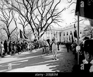 Funerale di Stato del Presidente Kennedy: Processione alla Cattedrale di San Matthewu2019s. Il cassero trainato da cavalli nella processione funeraria del presidente John F. Kennedy parte dalla Casa Bianca per la Cattedrale di San Matteo Apostolo. I cordoglio e i membri della linea di guardia di colore il vialetto del prato del Nord. White House, Washington, D.C. Foto Stock