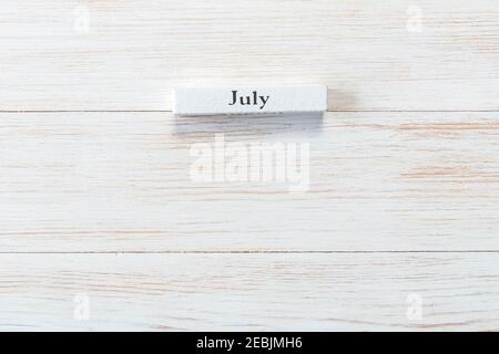 Whine blocco di legno di calendario con mese di luglio su sfondo vintage. Iscrizione luglio su tavola di legno. Vista dall'alto. Spazio di copia. Mockup per gli eventi del calendario Foto Stock