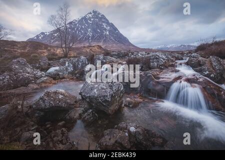 Moody paesaggio dell'iconica Buachaille Etiv Mor e cascata del fiume Coupall a Glencoe nelle Highlands scozzesi. Foto Stock