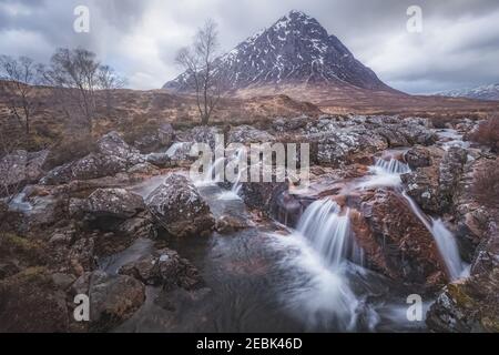Moody paesaggio dell'iconica Buachaille Etiv Mor e cascata del fiume Coupall a Glencoe nelle Highlands scozzesi. Foto Stock