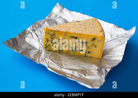 Pezzo di formaggio ammuffito su sfondo blu Foto Stock