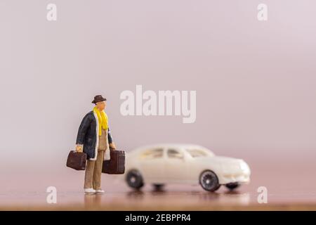 Persone in miniatura - borsa da trasporto uomo d'affari in piedi sul pavimento con sfondo bianco offuscato auto. Concetto di viaggio e affari. Foto Stock