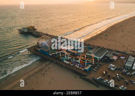 Molo di Santa Monica, Los Angeles dall'alto al bellissimo tramonto dell'ora d'oro a luci arancioni e ruota panoramica con vista sull'oceano e le onde che si infrangono Foto Stock