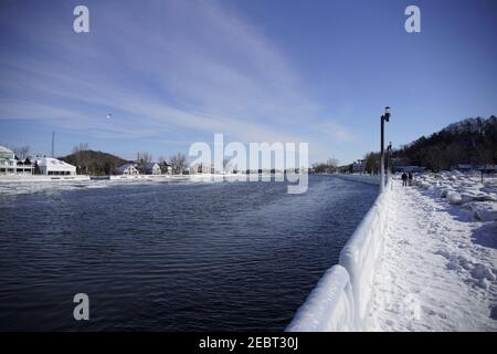 Grand Haven, Michigan, febbraio 2021, ringhiere e lampioni ricoperti di ghiaccio, lungo il sentiero innevato del molo, acqua invernale Foto Stock