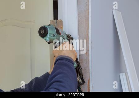 Costruzione delle porte interne di montaggio di telaio di legno in operaio con la pistola per unghie Foto Stock