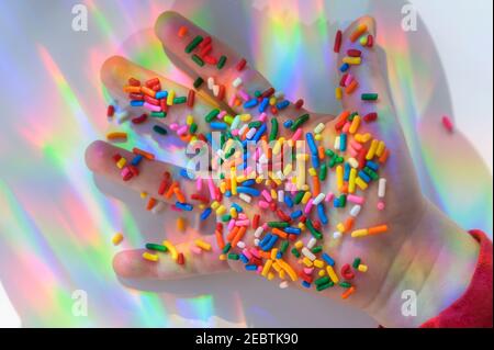 La mano tiene gli spruzzi con i riflessi colorati Foto Stock