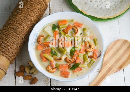 Stufato di mutton, zuppa di pollo stufato piatto laterale per Appam, pane, cibo per la colazione Kerala. Cibo indiano. Christian Natale cibo donna mano prendere curry piccante Foto Stock