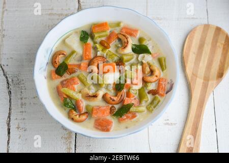 Stufato di mutton, zuppa di pollo stufato piatto laterale per Appam, pane, cibo per la colazione Kerala. Cibo indiano. Christian Natale cibo donna mano prendere curry piccante Foto Stock