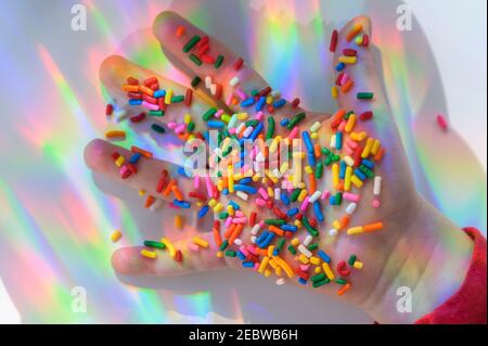 La mano tiene gli spruzzi con i riflessi colorati Foto Stock