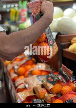 Pico - Robertson, CA USA - Jan 20, 2021: Primo piano vista di una mano di un uomo che raccoglie un sacco di arance di sangue nei Ralph's. Foto Stock