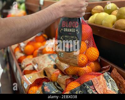 Pico - Robertson, CA USA - Jan 20, 2021: Primo piano vista di una mano di un uomo che raccoglie un sacco di arance di sangue nei Ralph's. Foto Stock