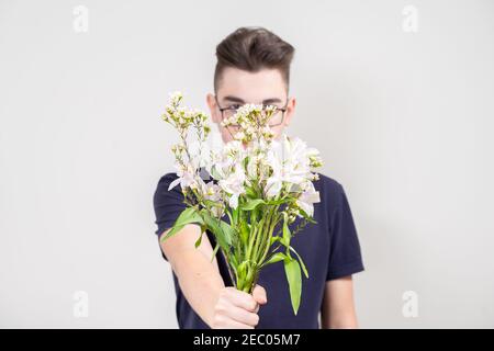 un giovane tiene fuori un mazzo di fiori bianchi. fuoco sui fiori Foto Stock