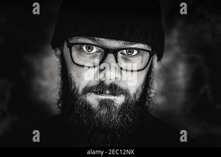 ritratto in bianco e nero di un uomo con barba e occhiali, primo piano, studio Foto Stock
