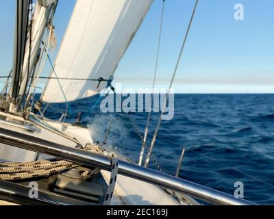 Yacht a vela lontano dalle teste del porto di Sydney, in una giornata tranquilla e soleggiata. Vista dall'abitacolo della barca sull'orizzonte, con l'oceano calmo davanti Foto Stock