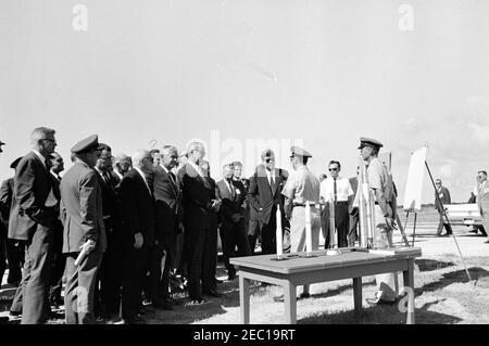 Visita delle installazioni della NASA: Cape Canaveral Florida, 14:31. Il presidente John F. Kennedy (indossando gli occhiali da sole) fa un giro del complesso di lancio del Titan alla stazione dell'aeronautica di Cape Canaveral, Cape Canaveral, Florida. Direttore delle operazioni di Range Safety con la gamma di test Eastern alla base dell'aeronautica di Patrick, il colonnello Dan F. Thompson (al centro a destra, di nuovo alla telecamera), il presidente Kennedy; i modelli dei missili Titan II e Titan III siedono sul tavolo in primo piano. Anche nella foto: Amministratore associato della National Aeronautics and Space Administration (NASA), Dr. Robert C. Seamans, Jr.; Comandante di t Foto Stock