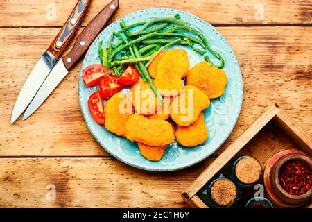 Deliziosi bocconcini di pollo fritti con cowpea sul piatto Foto Stock