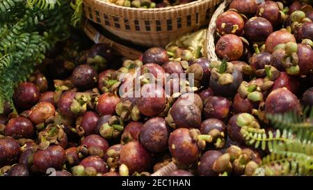 Frutta e verdura su stalla rustica. Frutta e verdura fresche mature e assortite poste su stalla orientale rustica nel mercato. Mang porpora tropicale dolce Foto Stock