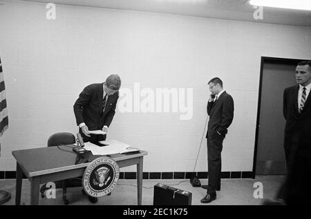 Viaggio della campagna del Congresso: St. Paul, Minnesota, indirizzo telefonico per un raduno a St. Cloud. Il presidente John F. Kennedy si prepara a esprimere le sue osservazioni per telefono a un raduno della campagna del Congresso a St. Cloud, Minnesota. Joe Taylor, funzionario della White House Communications Agency (WHCA), si trova all'estrema destra. Minneapolis-St Paul International Airport Terminal, Minnesota. Foto Stock