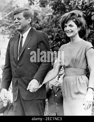 Visita dei partecipanti alla Conferenza della Campagna 1962 per le Donne democratiche, alle 9:35. Il presidente John F. Kennedy e la First Lady Jacqueline Kennedy si levano su una piattaforma speakersu2019 durante una visita con i partecipanti alla Conferenza della Campagna per le Donne democratiche del 1962. South Lawn, Casa Bianca, Washington, D.C. Foto Stock