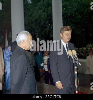 Cerimonia di arrivo del Dr. Sarvepalli Radhakrishnan, Presidente dell'India, 11:40. Il presidente John F. Kennedy, durante le cerimonie di arrivo, fa un'osservazione di benvenuto al presidente dell'India, il dottor Sarvepalli Radhakrishnan (a sinistra). In background: Shobha u201cForiu201d Nehru (moglie dell'Ambasciatore Indiano negli Stati Uniti, B. K. Nehru); Kitty Galbraith (moglie dell'Ambasciatore degli Stati Uniti in India, John Kenneth Galbraith); agente del Servizio Segreto della Casa Bianca, Roy Kellerman. Portico Nord, Casa Bianca, Washington, D.C. Foto Stock