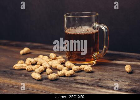 tazza di birra su un tavolo di legno arachidi in conchiglie primo piano su bevande alcoliche Foto Stock