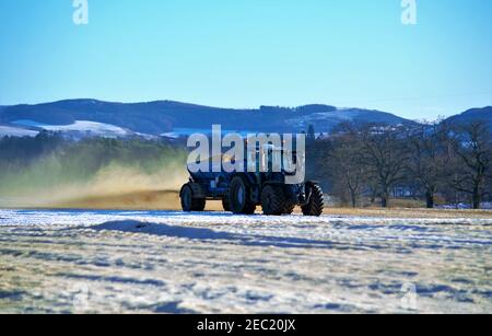 Trattore Valtra T194 e Agri-Spread AS65 che sparge calce su terreni innevati, Meikleour Estate, Blairgowrie, Perthshire, Scozia Foto Stock