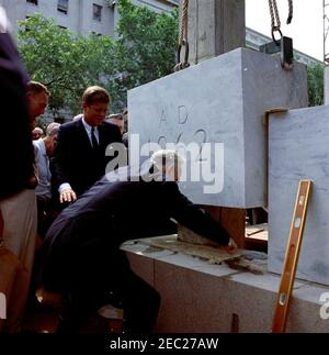 Cerimonia di posa Cornerstone, edificio degli uffici della Casa di Rayburn, 10:28. Il Presidente John F. Kennedy guarda il Presidente della Camera dei rappresentanti e il Presidente della Commissione per la costruzione degli uffici della Camera, John W. McCormack (Massachusetts), partecipare alla cerimonia di posa della pietra angolare per il Rayburn House Office Building, dedicato al defunto Presidente della Camera, Sam Rayburn. Il rappresentante romano C. Pucinski dell'Illinois guarda sopra (dietro la spalla del presidente Kennedyu2019s). Washington, D.C. Foto Stock