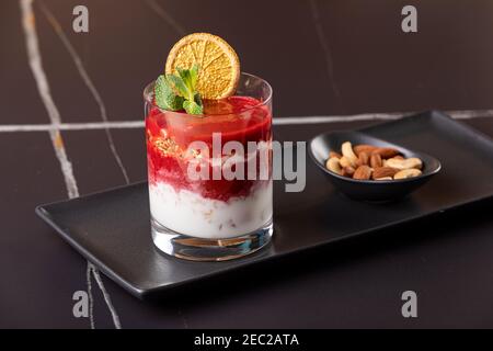 Dessert a strati con frutta, noci e formaggio cremoso in vetro Foto Stock