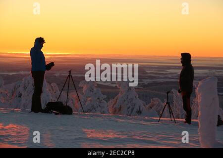 Schierke, Germania. 13 Feb 2021. I fotografi si levano alla luce del sole che sorge sul Brocken. Il freddo ghiacciato soffia oggi il vento sul Brocken. Temperature di meno 20 gradi sono state misurate sul picco di Harz più alto. Solo pochi escursionisti si avventurarono al Brocken alle temperature ghiacciate per l'alba. Credit: Matrhias Bein/dpa-Zentralbild/dpa/Alamy Live News Foto Stock