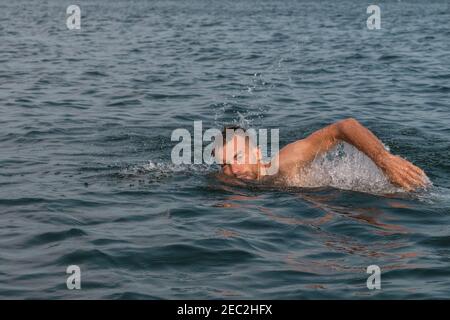 Giovane uomo sta nuotando veloce in acqua su soleggiato e. giorno caldo Foto Stock