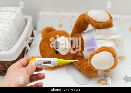 Orsacchiotto marrone con pannolino seduto nel lettino del bambino Foto Stock